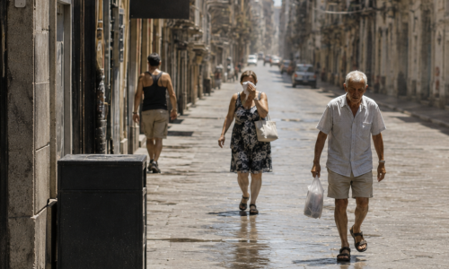 Persone camminano in una strada cittadina durante un'ondata di caldo estivo